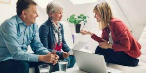 Smiling senior couple having a discussion with a professional advisor in a modern, well-lit office.