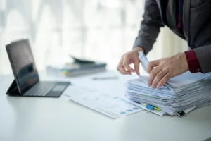 A businessperson organising a stack of business documents while preparing the business for sale