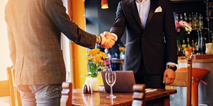 Men in suits shaking hands in a cafe